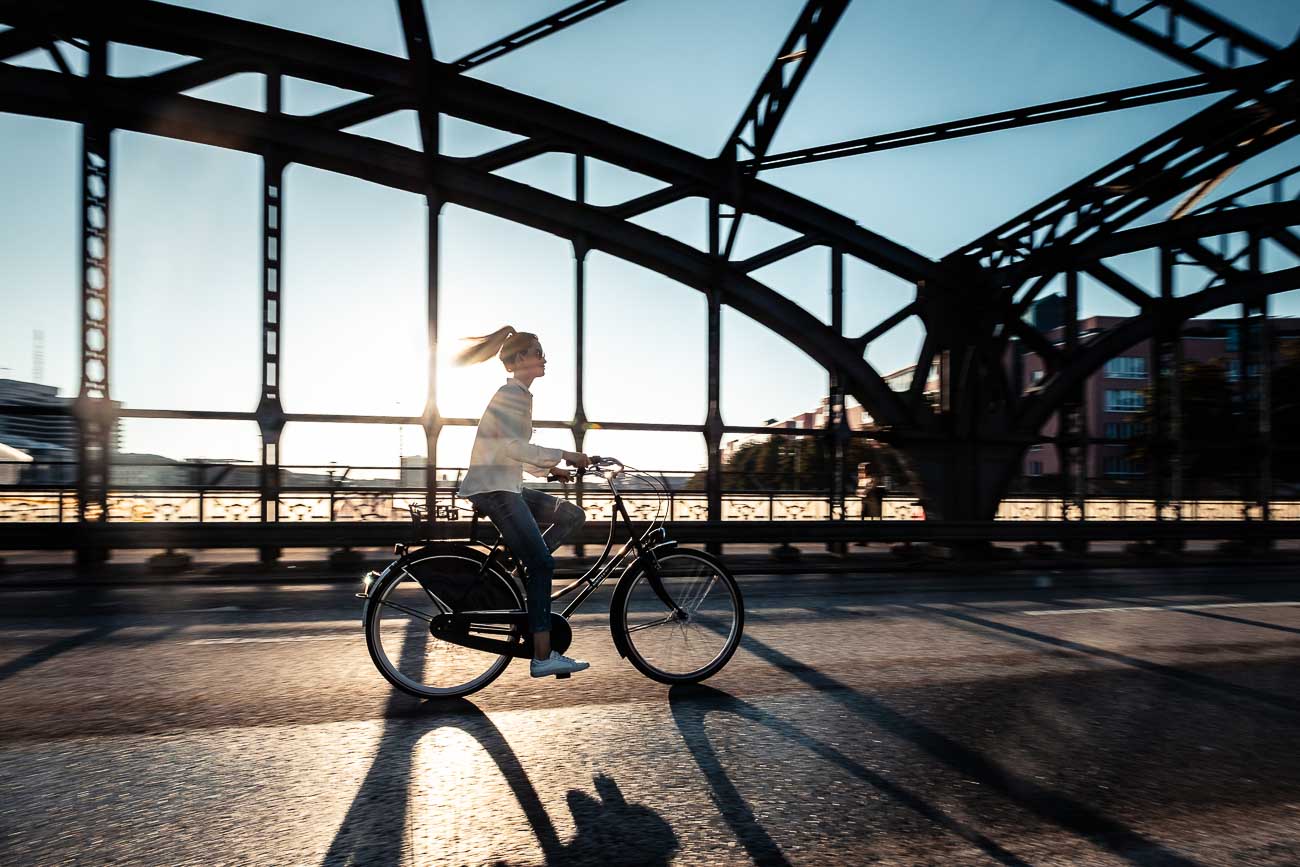 Junge Radlerin bei Sonnenuntergang auf der Hackerbrücke in München.